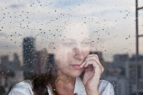 Kobieta wyglądająca przez okno podczas deszczu