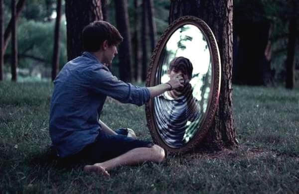 Chłopak w lesie dotyka lustra.