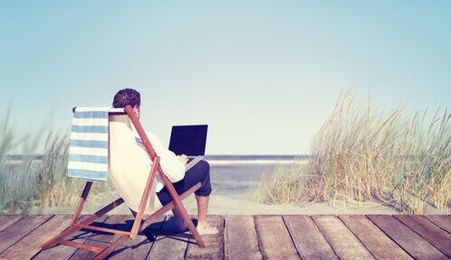mężczyzna siedzi z laptopem na plaży