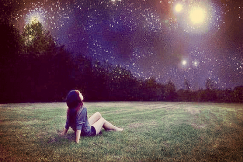 Zadawanie pytań - dziewzyna siedzi na trawie i patrzy na gwieżdziste niebo