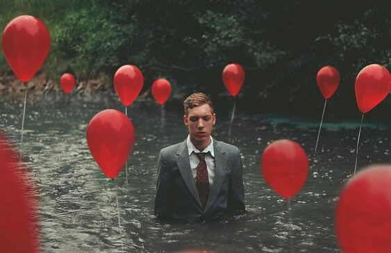 Mężczyzna w wodzie z czerwonymi balonikami.