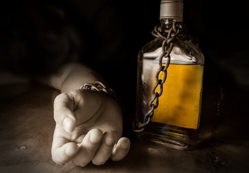 Ręka przykuta do butelki z alkoholem