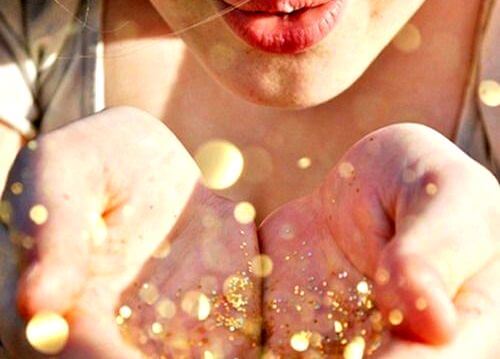 Kobieta zdmuchuje brokat z dłoni