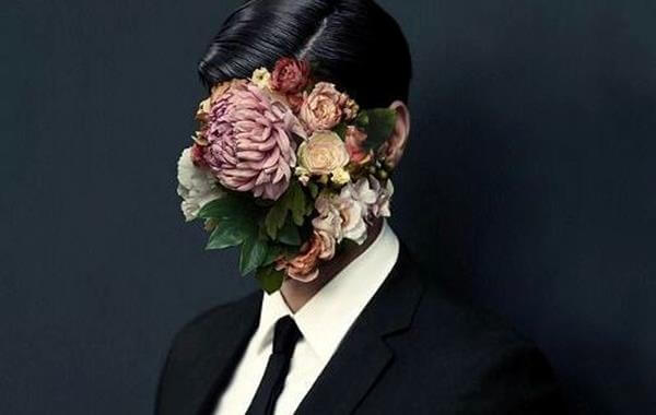 Mężczyzna z twarzą zakryta kwiatami.