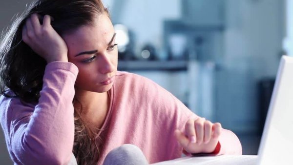 Smutna nastolatka przed komputerem.