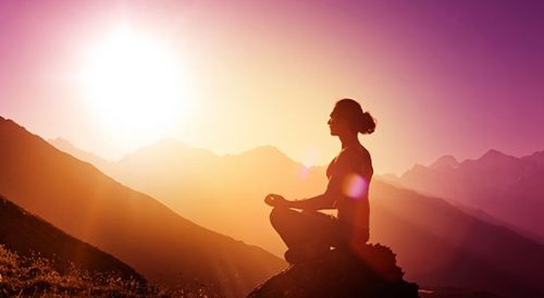 Mantry medytacyjne - kobieta medytuje w górach