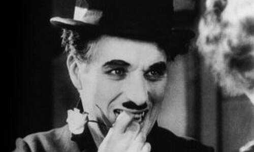 Charles Chaplin uśmiechnięty z kwiatem w dłoni