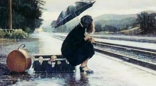 Kobieta z parasolem siedzi na walizce przy torach