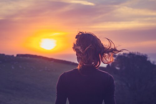 Znaczenie życia w teraźniejszości - kobieta patrzy na zachód słońca.