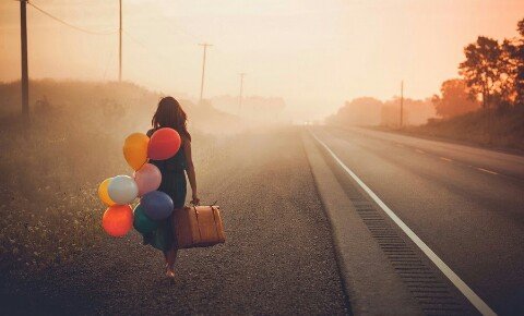Dziewczyna z kolorowymi balonikami i walizką.