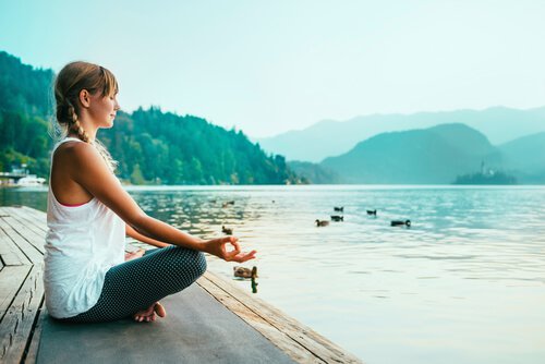 Kobieta medytująca nad jeziorem.