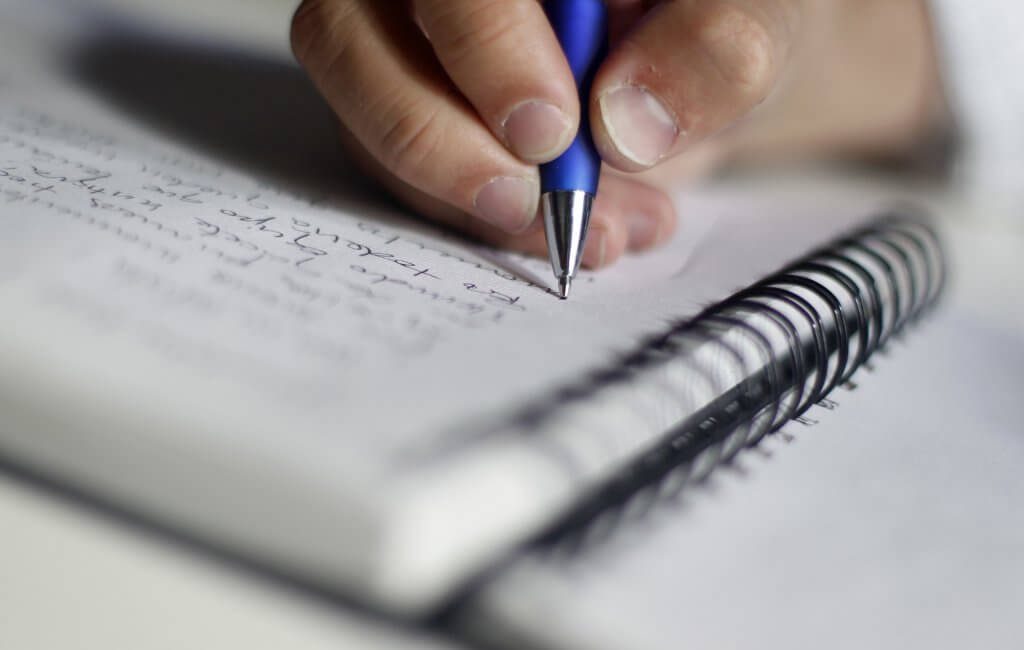ręka pisząca w zeszycie