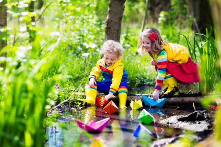 Dzieci puszczają kolorowe statki nad rzeką