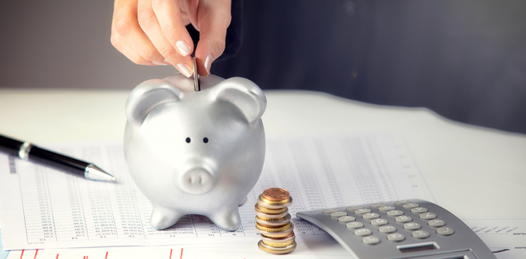 ręka wrzucająca monety do skarbonki