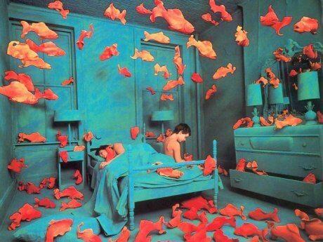 Delirium - człowiek siedzi na łóżku a wokół latają ryby