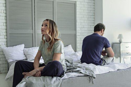 Niezadowolone pary - kobieta i mężczyzna siedzą tyłem do siebie na łóżku