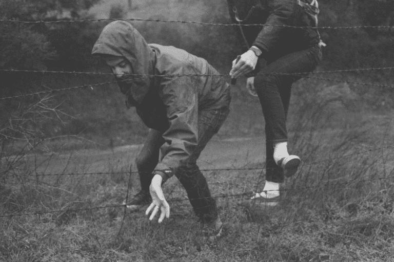 Przyjaciele przechodzący przez zasieki.