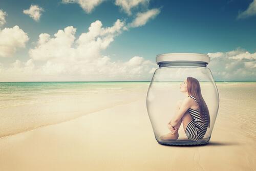 Unikanie doświadczania - kobieta na plaży siedzi zamknięta w szklanym słoiku