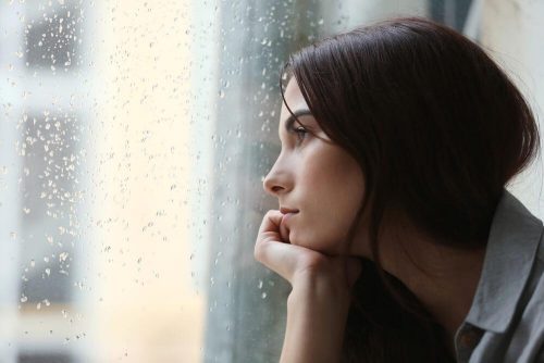 Smutna kobieta patrzy przez okno