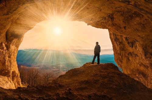 Człowiek stojący przy wejściu do jaskini.