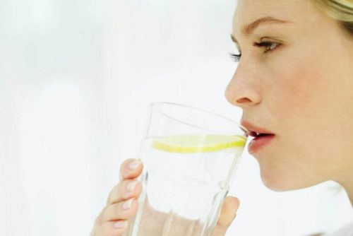 kobieta pije wodę z cytryną