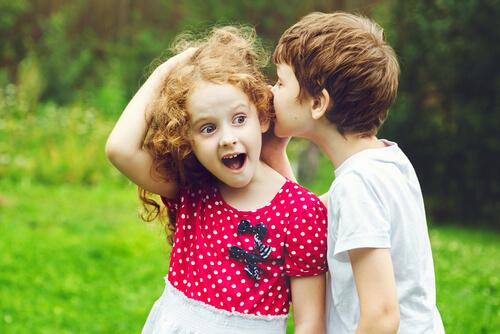 Chłopiec szepcze dziewczynce do ucha