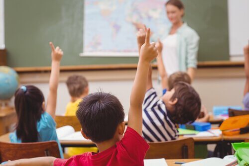 Edukacja - dzieci w klasie podnoszą ręce
