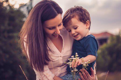 Mama trzyma syna na ręku i zbiera kwiaty