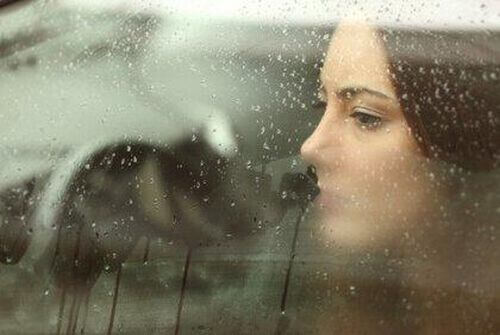 Kobieta przy oknie w deszczu