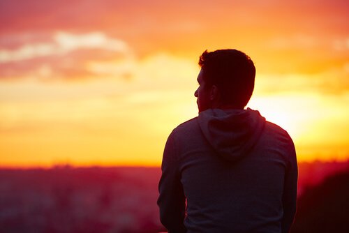 Mężczyzna stojący tyłem na tle zachodzącego słońca