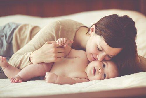 Szczęśliwa mama całuje niemowlę - macierzyństwo