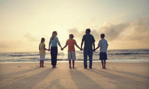 Rodzina na plaży trzyma się za ręce poprawiając klimat emocjonalny