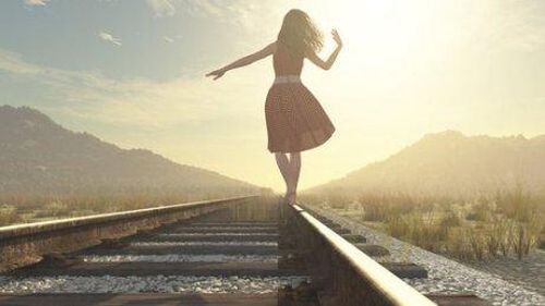 Kobieta idzie wzdłuż torów kolejowych