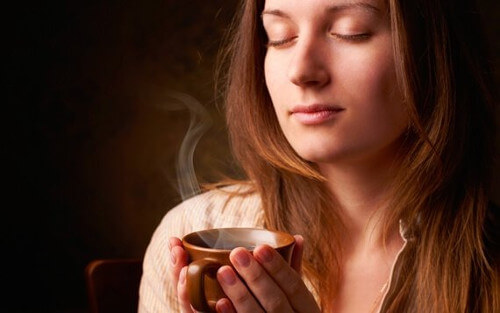 Kobieta wdycha zapach kawy.