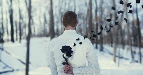 mężczyzna z czarną różą za plecami