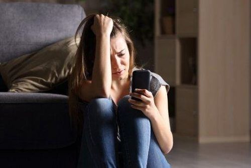 Zestresowana kobieta patrzy na telefon komórkowy