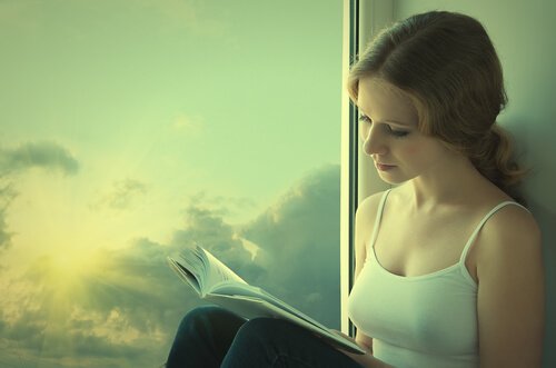 kobieta czytająca książkę przy oknie