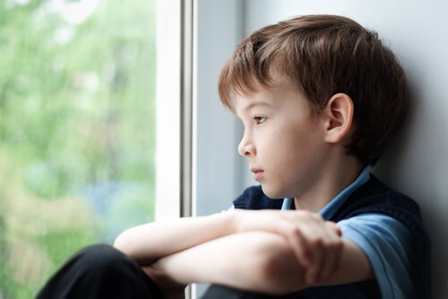 Smutny chłopiec patrzący przez okno