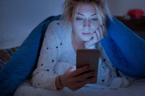 Kobieta patrzy w łóżku na ekran telefonu