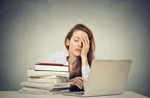 Przemęczona kobieta przy biurku - syndrom Kasandry