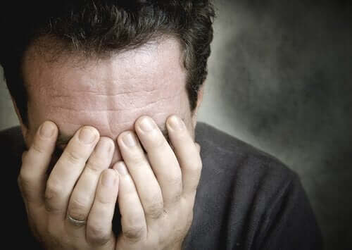 Zmartwiony mężczyzna trzyma twarz w dłoniach