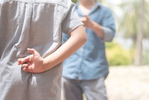 Chłopiec krzyżuje palce za plecami i mówi kłamstwa