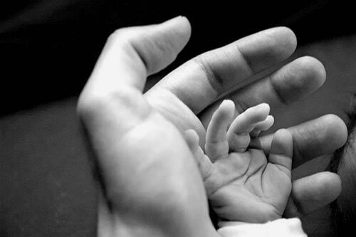 Ręka dziecka i dorosłego wyraża przywiązanie do dziecka