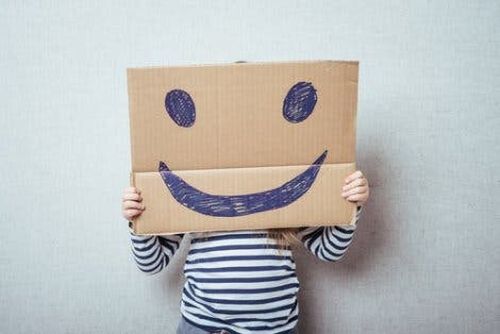 Dziecko za kartonem z narysowanym uśmiechem