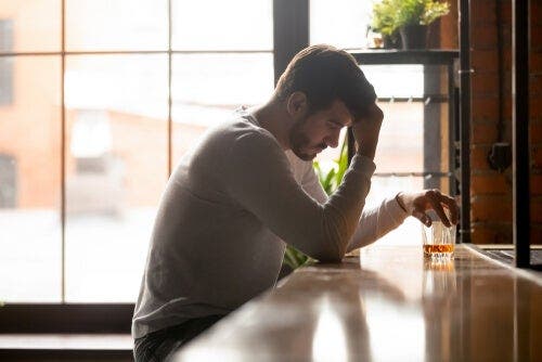 Mężczyzna przy barze ze szklanką alkoholu - oszukiwanie samego siebie i alkoholizm
