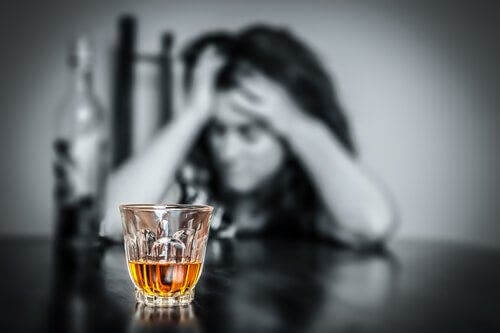 Załamana kobieta patrząca na alkohol