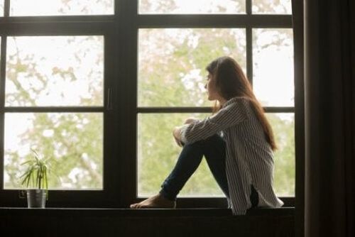 Kobieta siedzi przy oknie i rozmyśla nad swoim życiem