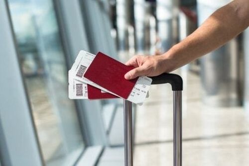 Osoba z walizką na lotnisku z dwoma paszportami w dłoni