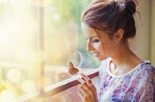 Kobieta przyglądająca się motylowi - wpływ na własne szczęście