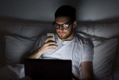 Mężczyzna z telefonem w łóżku - bezsenność cyfrowa